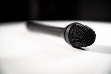 Siyah koyu gri muhabir çok yönlü dinamik mikrofon ses donanımı koyu kırmızı arka plan fotokopi alanı ve metin için odası olan beyaz bir masada oturuyor..