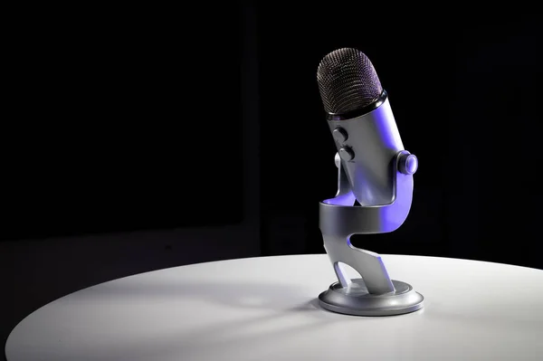 Üzerinde ayarlanabilir masa üstü durağı olan gri USB yoğunlaştırıcı mikrofon koyu renkli parlak renkli ve fotokopi alanı olan beyaz bir kontrast odasında duruyor.