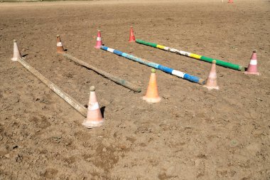 Accessories for horse trainings and events in rural equestrian training centre. Image of an empty training field. Barriers for schooling horses as a background. clipart