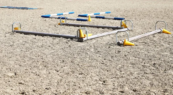 Accessories for horse trainings and events in rural equestrian training centre. Image of an empty training field. Barriers for schooling horses as a background.