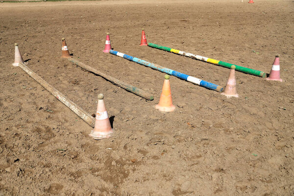 Accessories for horse trainings and events in rural equestrian training centre. Image of an empty training field. Barriers for schooling horses as a background.