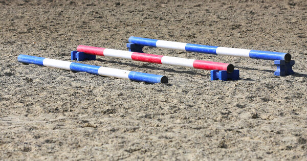 Accessories for horse trainings and events in rural equestrian training centre. Image of an empty training field. Barriers for schooling horses as a background.