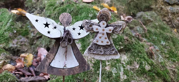 Beautiful angel decorations with wings on back in vintage garden. Angel statue against green mossy stone. Interior of abandoned garden with angel statue with mossy green leaves