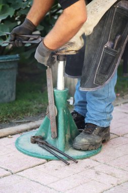 Bilinmeyen demirci yazın at nalı ile dışarıda çalışıyor.