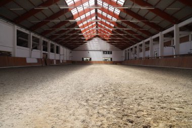 Atlar ve biniciler için boş bir binicilik salonunun fotoğrafı. Binicilik okulu bütün gün ata binmek ve ata binmek için uygundur.