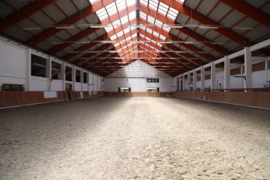 Atlar ve biniciler için boş bir binicilik salonunun fotoğrafı. Binicilik okulu bütün gün ata binmek ve ata binmek için uygundur.