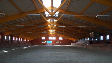 Atlar ve biniciler için boş bir binicilik salonunun fotoğrafı. Binicilik okulu bütün gün ata binmek ve ata binmek için uygundur.