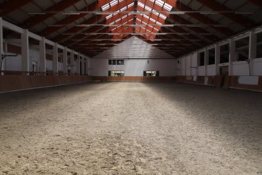 Atlar ve biniciler için boş bir binicilik salonunun fotoğrafı. Binicilik okulu bütün gün ata binmek ve ata binmek için uygundur.