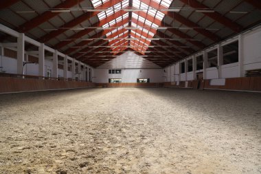 Atlar ve biniciler için boş bir binicilik salonunun fotoğrafı. Binicilik okulu bütün gün ata binmek ve ata binmek için uygundur.