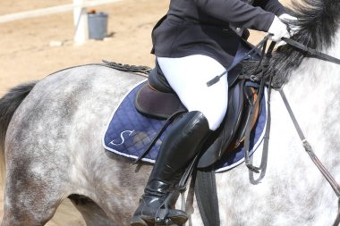 Yaz mevsiminde, atlama yarışında yarışan bilinmeyen bir yarışmacı. Atlayan atı eyer altında eylem halinde göster