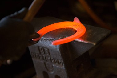 Nalbantta örs üzerinde sıkı çalışma. Parlayan çelik at nalı. Demirci sıcak bir at nalı döver.