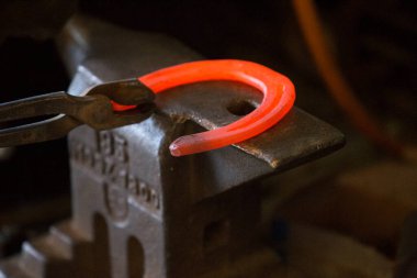 Nalbantta örs üzerinde sıkı çalışma. Parlayan çelik at nalı. Demirci sıcak bir at nalı döver.