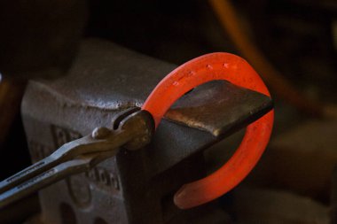 Nalbantta örs üzerinde sıkı çalışma. Parlayan çelik at nalı. Demirci sıcak bir at nalı döver.