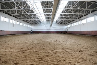Atlar ve biniciler için kapalı binicilik salonu. Binicilik okulu binicilik ve atlama için uygundur. Binicilik eğitimine hazır insanlar olmadan arenanın iç kısımları korunuyor.