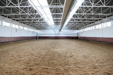 Atlar ve biniciler için kapalı binicilik salonu. Binicilik okulu binicilik ve atlama için uygundur. Binicilik eğitimine hazır insanlar olmadan arenanın iç kısımları korunuyor.