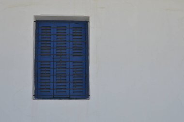 Beyaz duvardaki yalnız mavi pencere