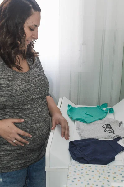 Mujer Embarazada Mirando Ropa Futuro Hijo —  Fotos de Stock