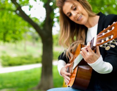Parkta gitar çalan güzel sarışın kız.