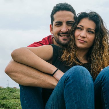 Genç çift parkta öpüşüyor ve gülüyor.