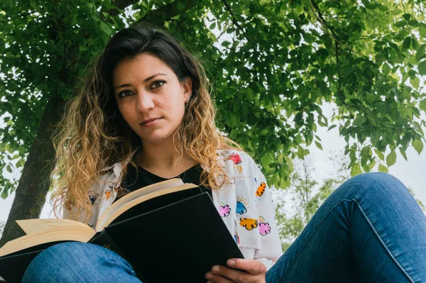 Parktaki bankta kitap okuyan güzel kız.