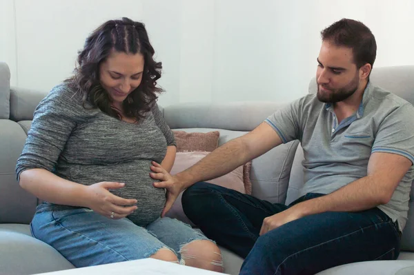 Embarazada Pareja Boda Sentado Sofá Mirando Tripa Sonriendo —  Fotos de Stock