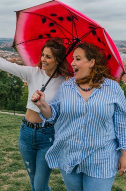 Parkta kırmızı şemsiyeli genç kızlar