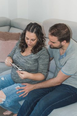 Hamile çift gelecekteki çocuklarının ultrasonuna bakıp gülümsüyor ve çok mutlu.