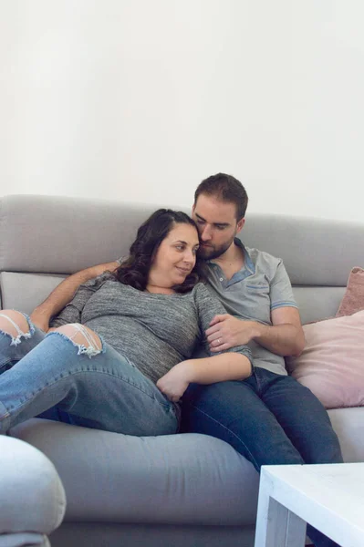 Pareja Embarazada Boda Sentada Sofá Mirándose Sonriendo —  Fotos de Stock