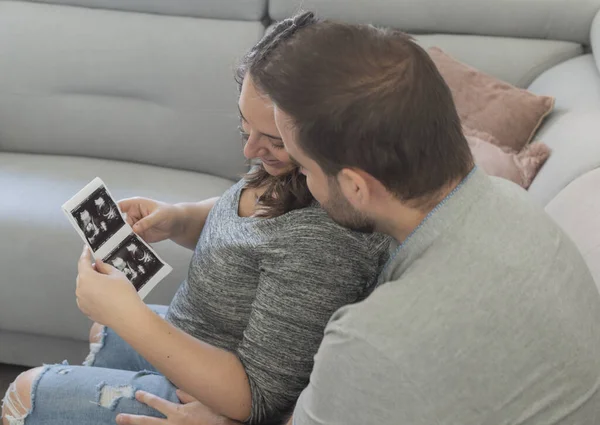 Pregnant couple looking at an ultrasound of their future child, smiling and very happy