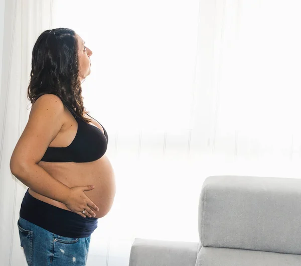 Těhotná Žena Dívá Okna Dotýká Břicha — Stock fotografie