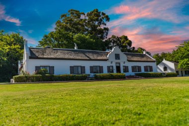 Franschhoek şarap vadisi ve Hollanda tarzı çiftlik evleri. Batı Afrika Burnu 'nda mavi gökyüzü altın bulutu.