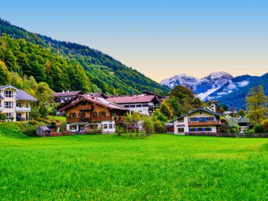 Ramsau bei Berchtesgaden 'in resimli dağlık evleri vadide yuva yapar ve arka planda görkemli karlı dağlar yükselir. Bavyera, Almanya