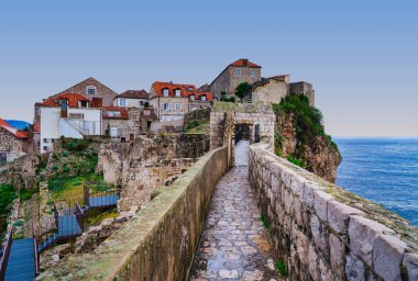 Dubrovnik 'in tarihi batı duvarları, açık günbatımında ikonik kırmızı çatılar ve Adriyatik Denizi' ne bakan Tower tepesine doğru esiyor. Dubrovnik, Hırvatistan
