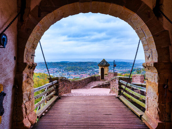 A scenic view of Eisenach town framed by the stone entrance archway of the historic Wartburg Castle. Thuringia, Germany