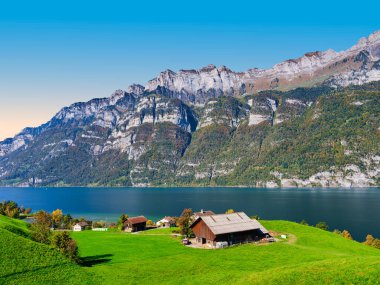 Quarten 'de yeşil otlaklar ve İsviçre' deki koyu mavi Walensee ve görkemli Churfirsten dağlarına bakan geleneksel bir ahır içeren pitoresk kırsal arazi.