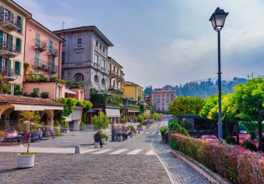 Bellagio 'daki ağaçlandırılmış Lungolago Europa gezinti alanının atmosferik görünümü canlı sonbahar yaprakları ve yayaların hayalet hareket bulanıklığı içerir.