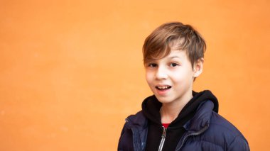 Turuncu arka planı olan sarışın çocuk portresi.