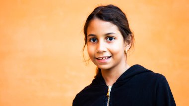 Turuncu arka planı olan esmer kız portresi.