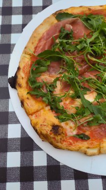 Siyah beyaz kareler üzerinde Prosciuto e rogula pizza.