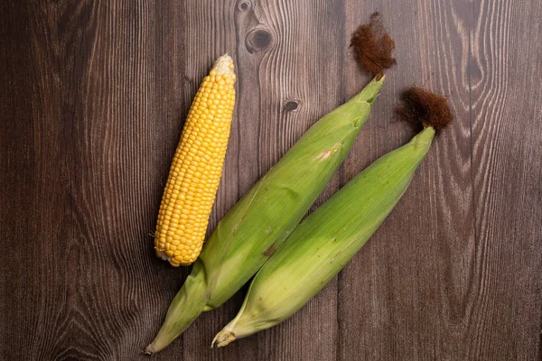 Čerstvé kukuřičné palice na plochém dřevěném pozadí — Stock fotografie