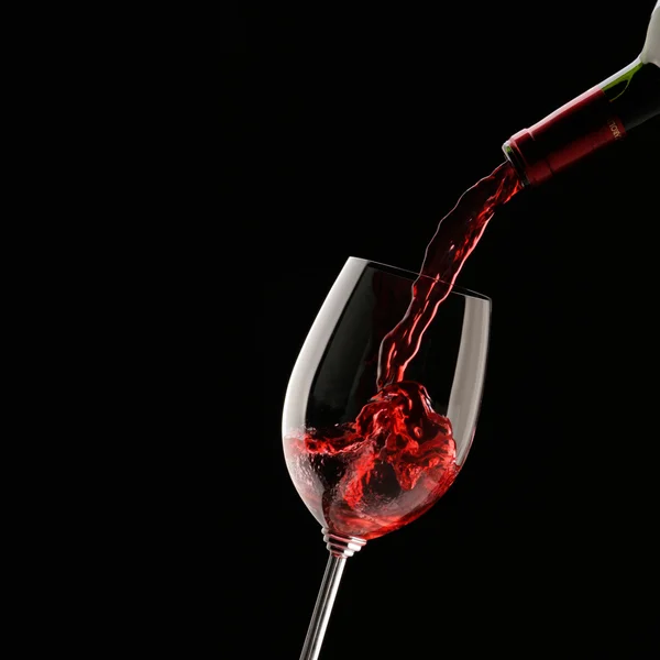 Öntés vörösboros pohár a fekete háttér — Stock Fotó