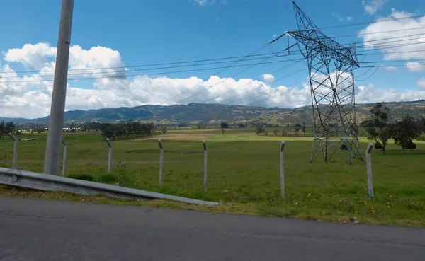 Elektrik kulesi ve hatlar bir tarlanın üzerinde ve ayrıca bir yol üzerinde