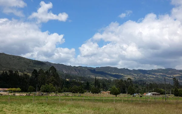 Clouds and a blue sky over a village in a valley under the hills