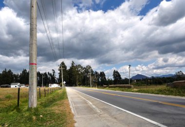 Dramatik bir gökyüzünün altındaki ve tarlaların ortasındaki otobanın yatay görüntüsü