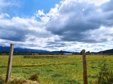 Çitlerin arkasında ve dramatik bir gökyüzünün altında geniş bir çiftlik.