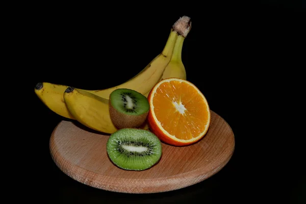 Kiwi Frutas Laranja Bananas Tábua Redonda Madeira Fundo Preto — Fotografia de Stock