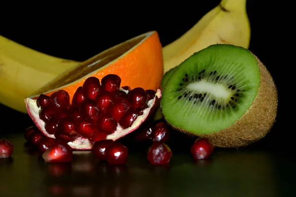 黒の背景に隔離された熱帯果実 ザクロ オレンジ キウイとバナナ — ストック写真
