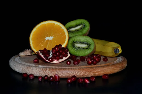 Tropische Früchte Auf Einem Runden Holzbrett Isoliert Auf Schwarzem Hintergrund — Stockfoto