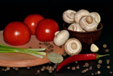 kırmızı domates, mantarlar, sarımsak, kırmızı biber tabakta, hepsi yuvarlak ahşap tahtada koyu arkaplanda