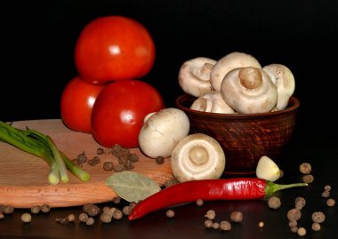 kırmızı domates, mantarlar, sarımsak, kırmızı biber tabakta, hepsi yuvarlak ahşap tahtada koyu arkaplanda